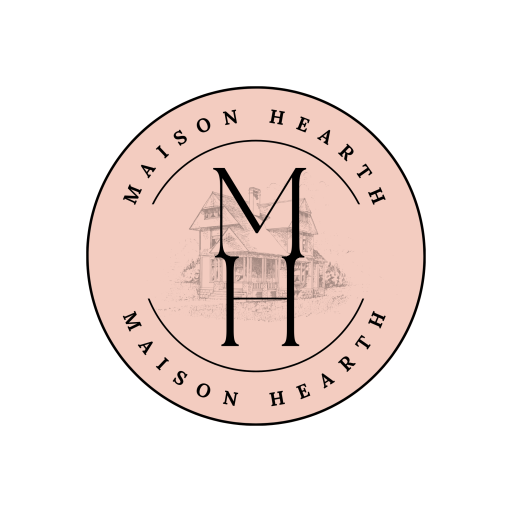 Circular pink Maison Hearth logo featuring a black “MH” monogram with a faint house illustration in the background and “Maison Hearth” written around the border.