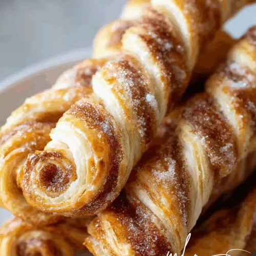 Close‑up of cinnamon‑sugar pastry twists with visible flaky layers and caramelized sugar.